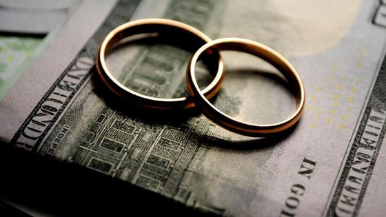 American money bill with engagement rings overtop